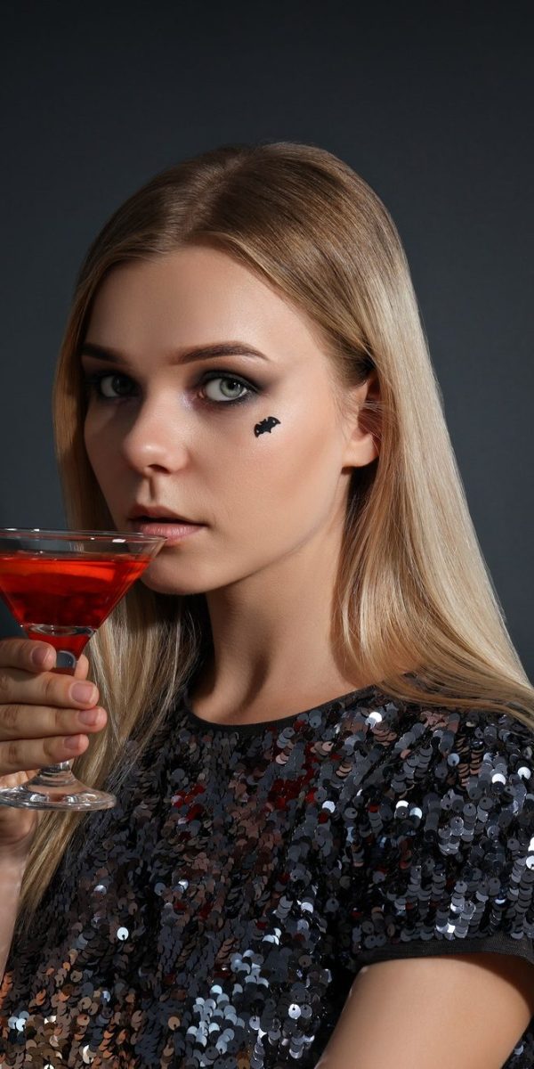 A girl at a party in the style of Halloween with a cocktail in her hands